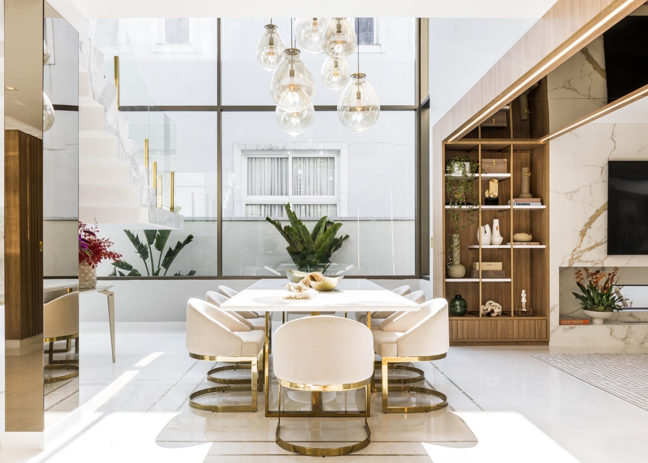 Sala de jantar luxuosa com mesa de jantar moderna de aço inox e oito cadeiras elegantes, destacando acabamentos de alto padrão, disponíveis na Moveca Decor