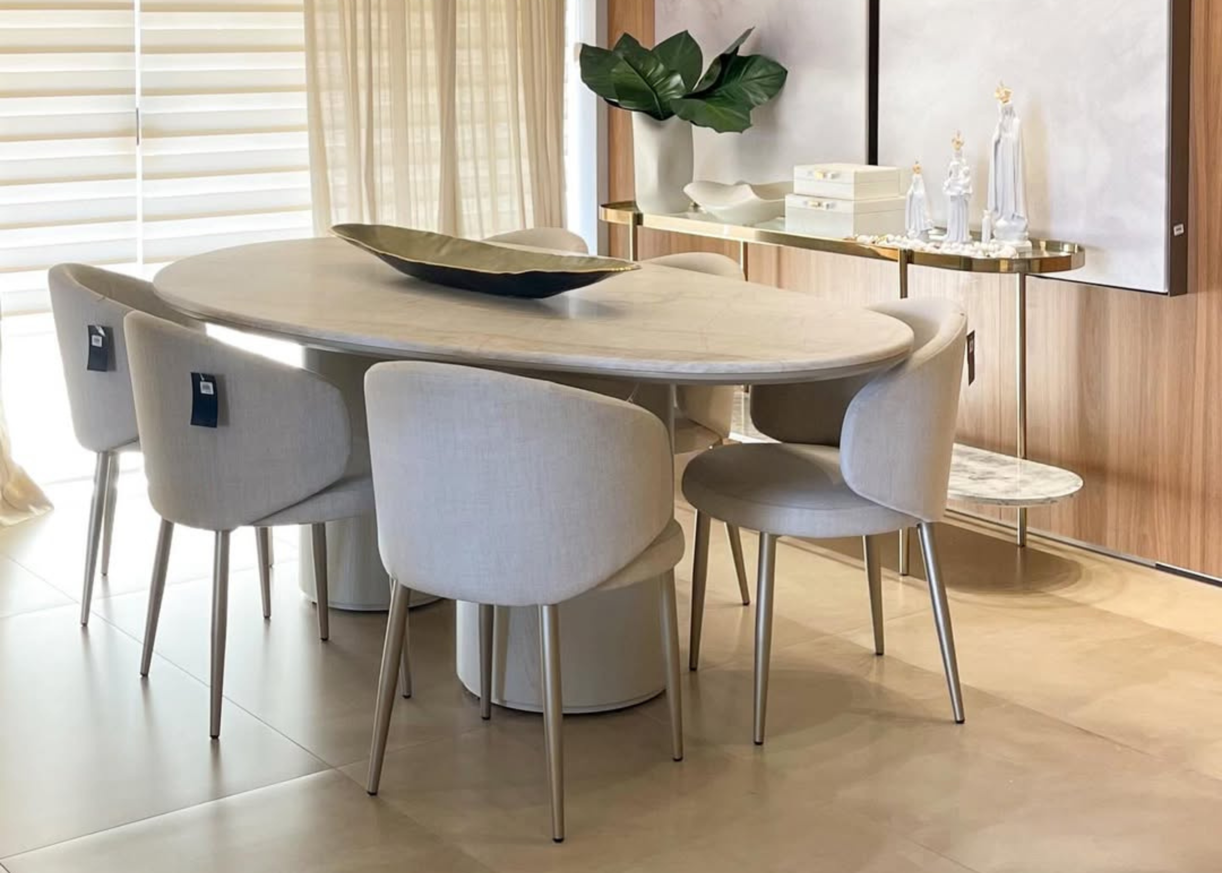 Mesa de Jantar Astrid com tampo oval orgânico em mármore e estrutura em lâmina de madeira de acabamento refinado.