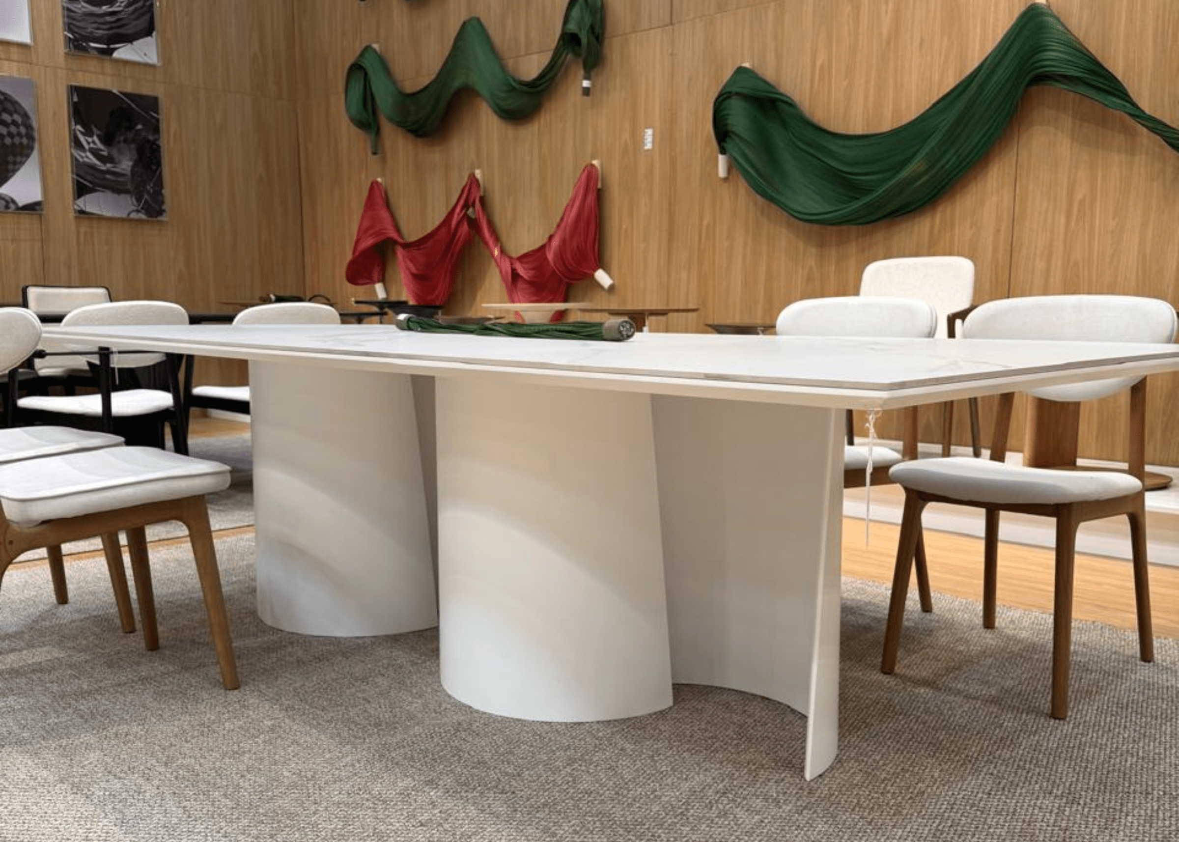 Mesa Atena com tampo em pedra sinterizada e base curva em MDF laqueado em ambiente contemporâneo.