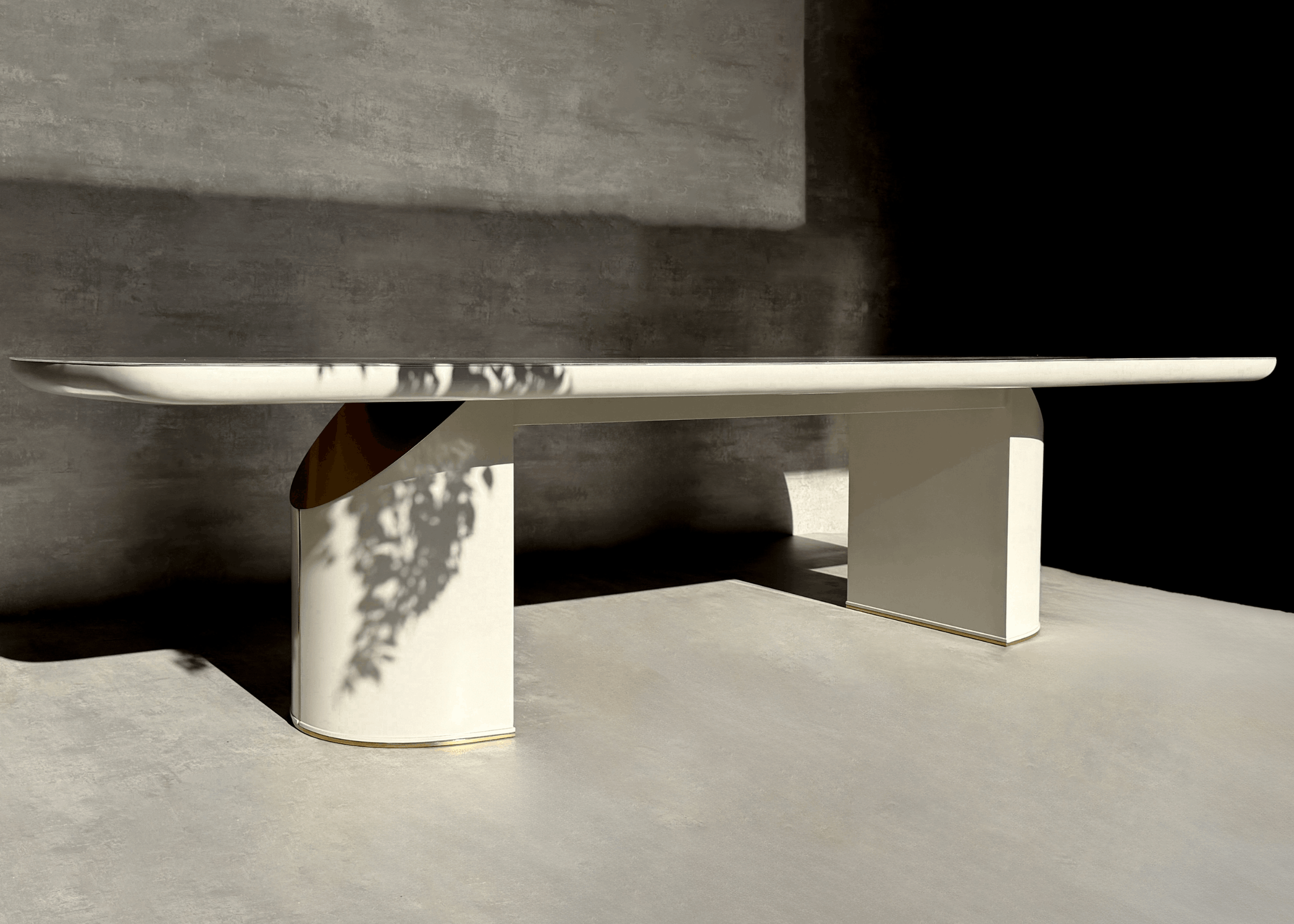 Detalhe da base da Mesa de Jantar Stein com acabamento em laca e aço inox, evidenciando o design escultural e contemporâneo da peça.