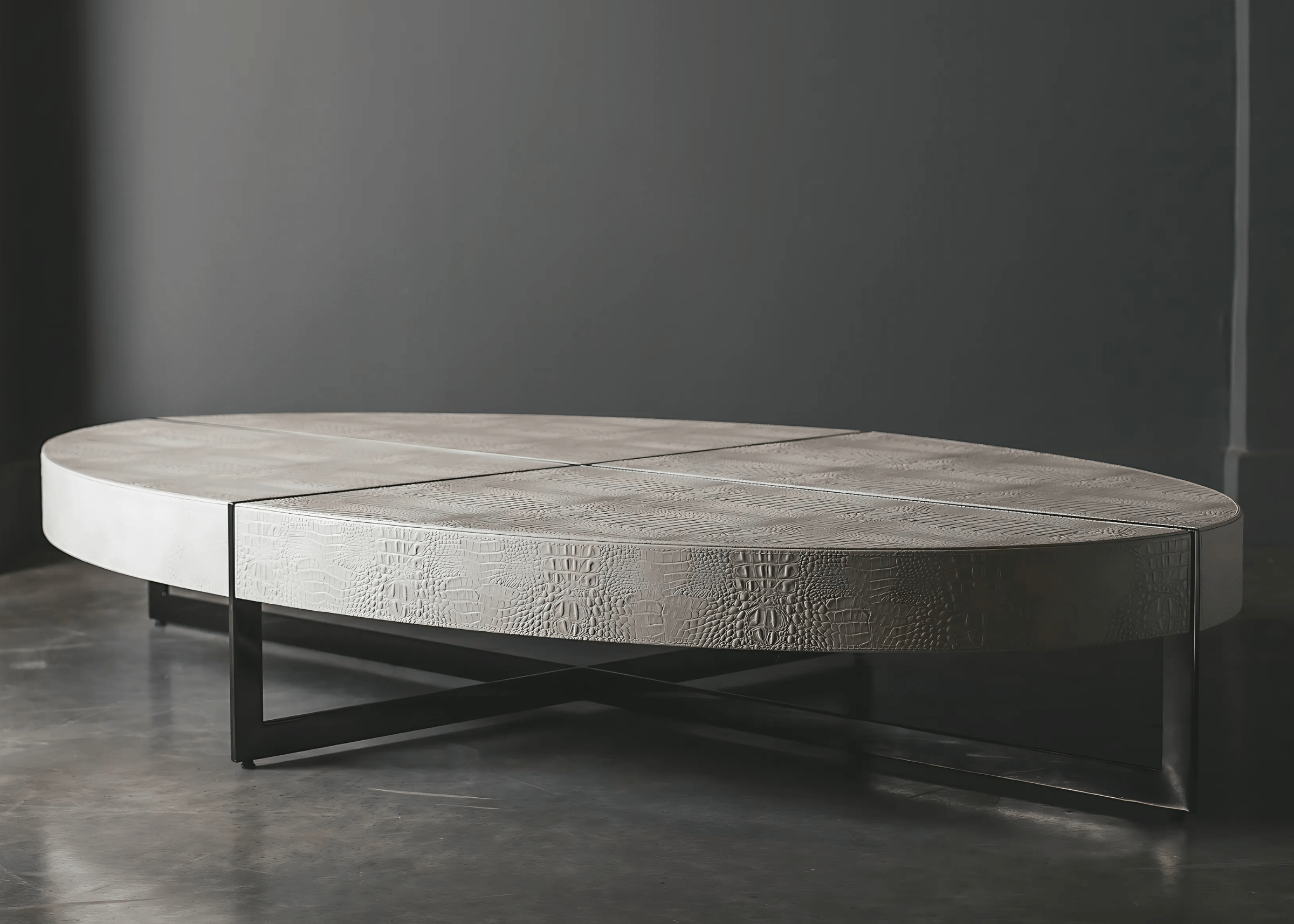 Mesa de Centro Martim com tampo oval em recouro e base cruzada em aço inox.