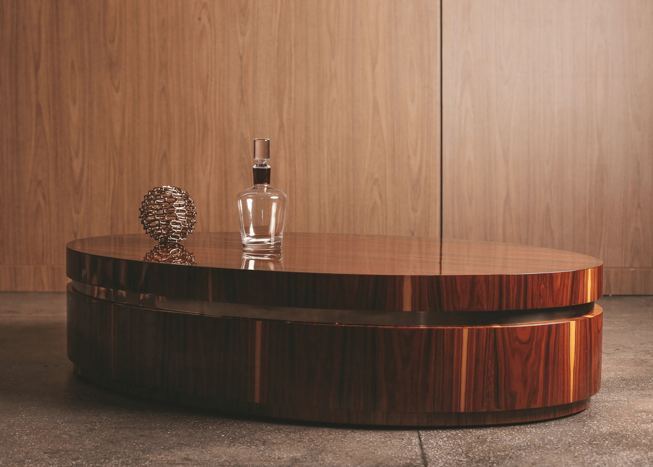 Sala sofisticada com a Mesa de Centro Alba Oval em destaque, combinando madeira e detalhe dourado.