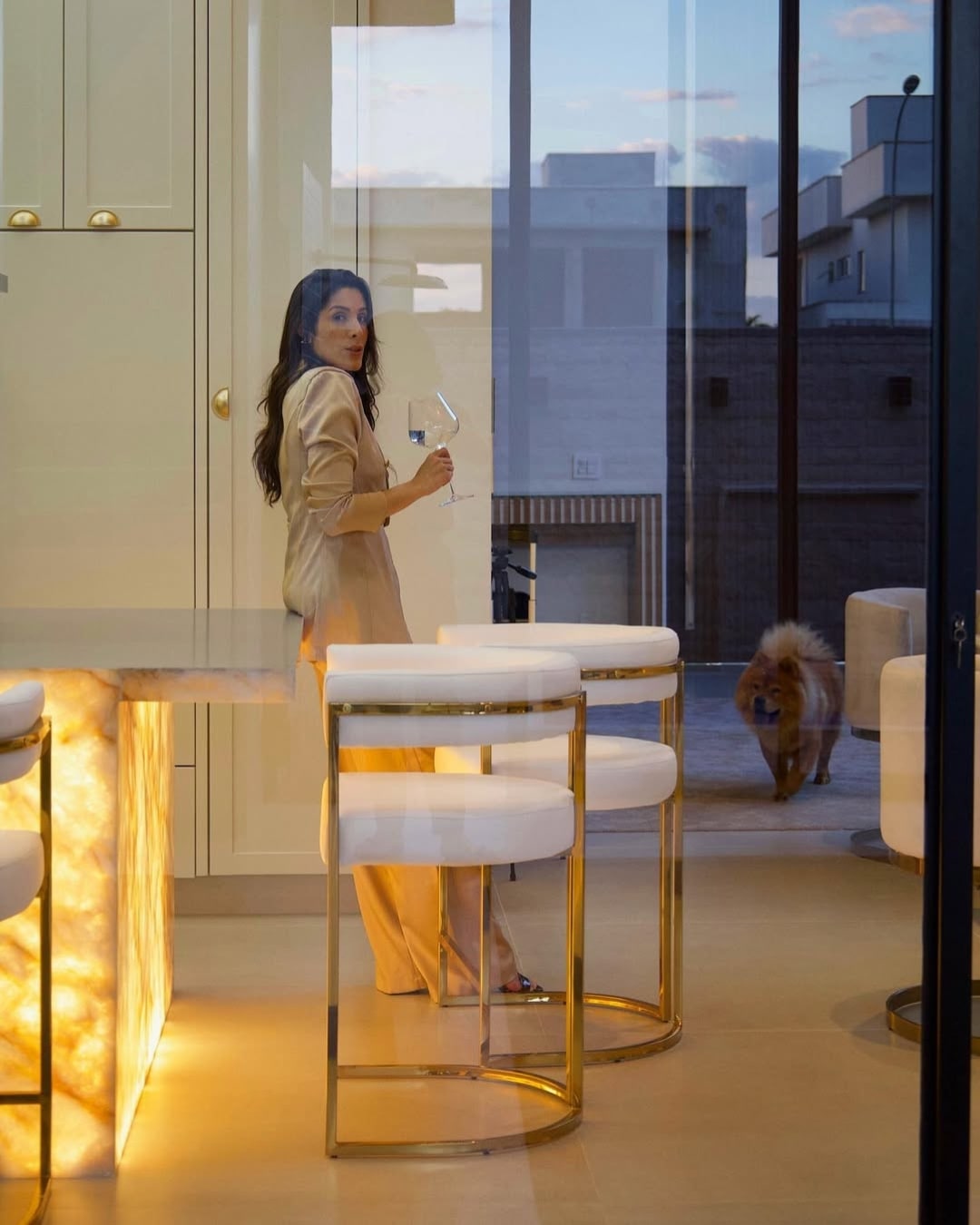 Banqueta alta Eldorado em bancada gourmet de luxo com estrutura dourada e estofada estofado off-white.