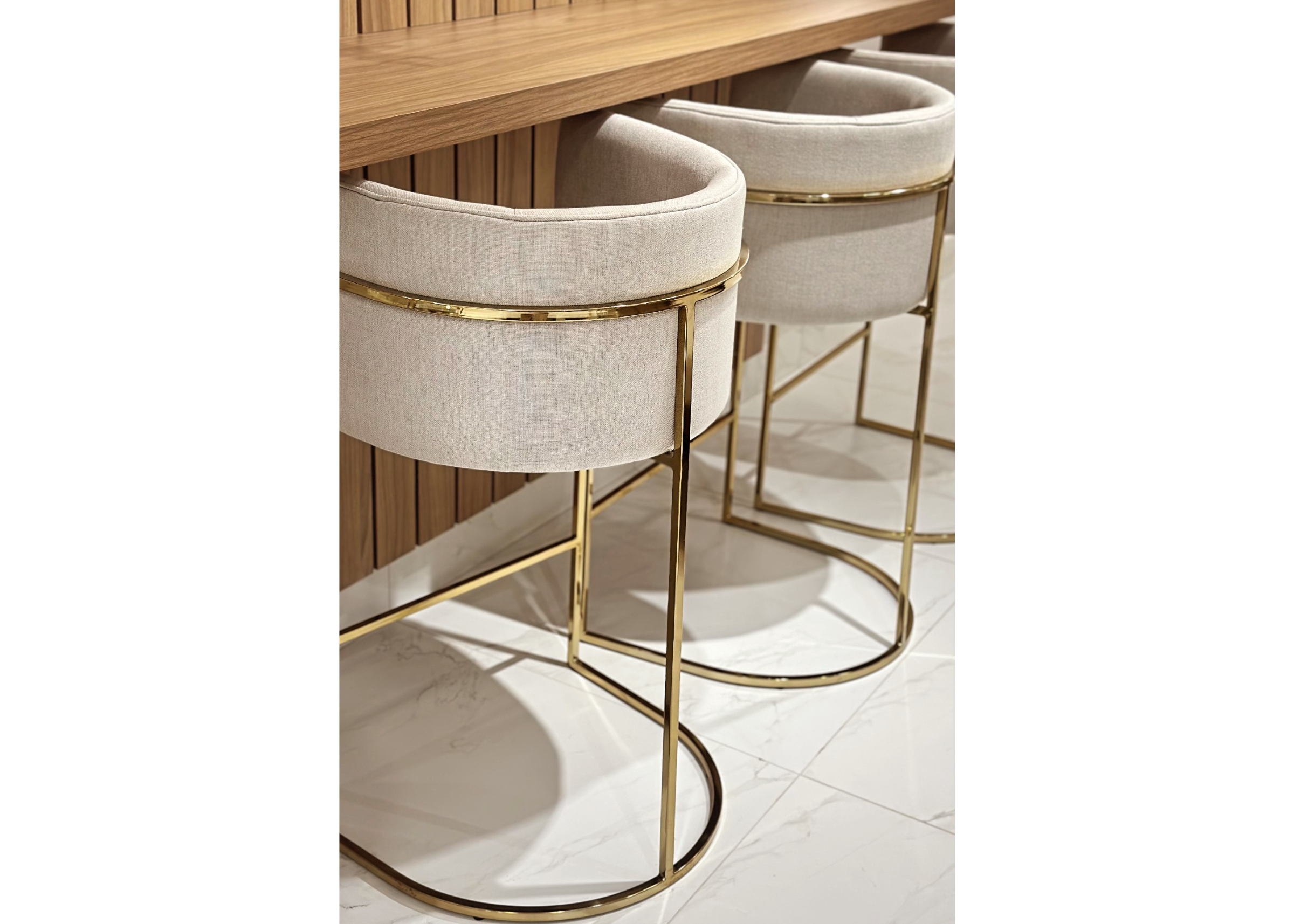 Banqueta Maria estofada em tecido linho, disposta em ambiente com bancada. Móvel elegante e confortável para cozinhas e espaços gourmet modernos.