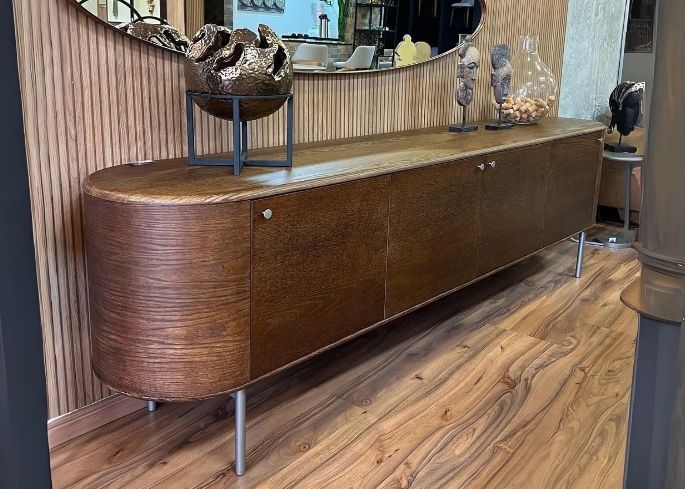 Buffet de quatro portas, luxuoso com acabamento em lâmina de madeira e cantos curvos, peça sofisticada para sala de jantar elegante.