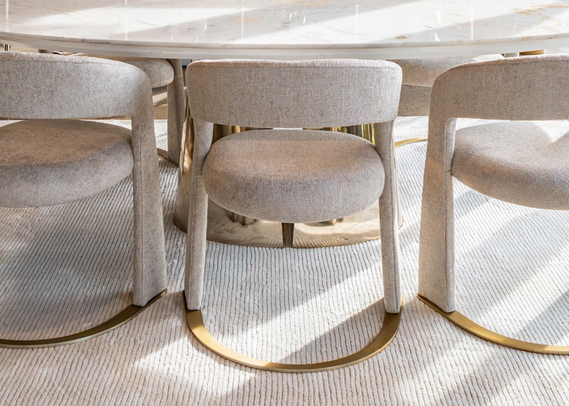 Cadeira de jantar Celeste com base em inox dourado e assento estofado, vista sobre fundo elegante. Design sofisticado para salas de jantar modernas.