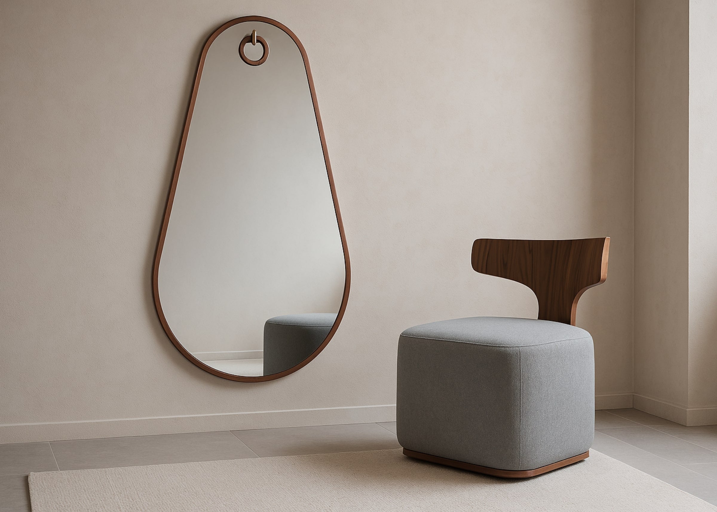 Ambiente moderno com o Espelho Arthemis de formato orgânico e moldura em madeira, acompanhado da Poltrona Charlie estofada em tecido cinza e encosto em madeira. Composição elegante e minimalista em sala de estar com tons neutros.