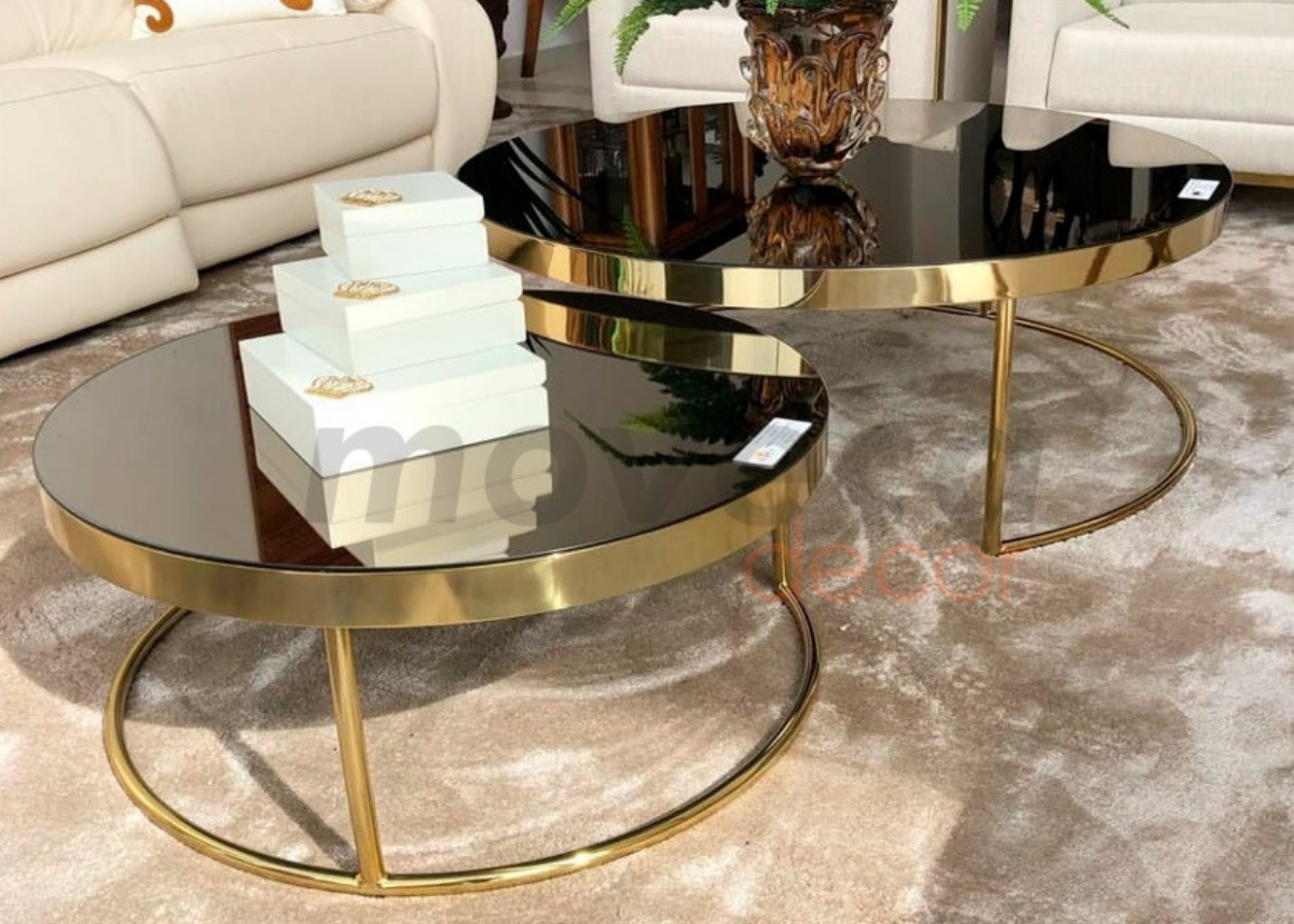 Mesa de centro com tampo laqueado preto e base em inox dourado, vista sobre sala de estar moderna. Peça sofisticada para salas de estar contemporâneas.