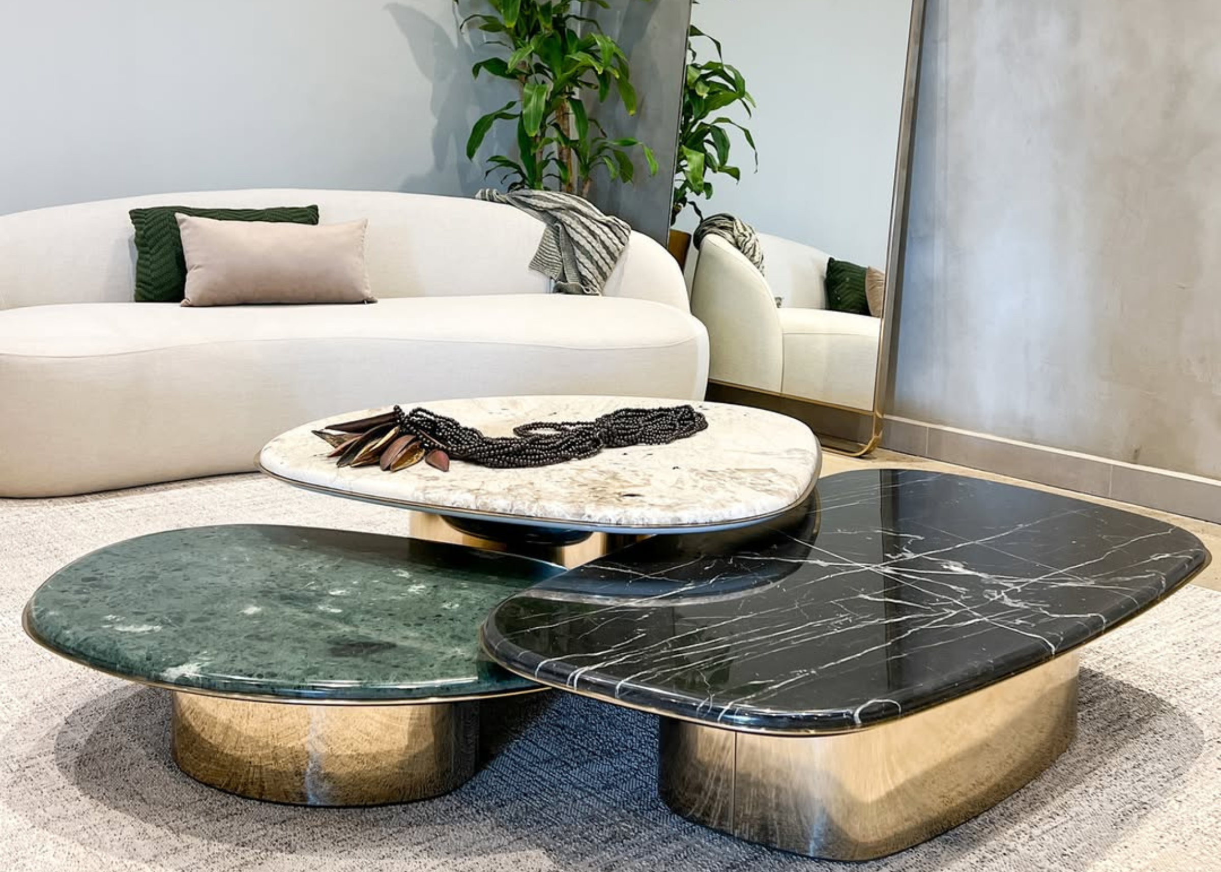 Mesa de centro orgânica modelo Majestosa com base em inox dourado e tampo em mármore. Peça imponente e sofisticada para salas de estar elegantes.