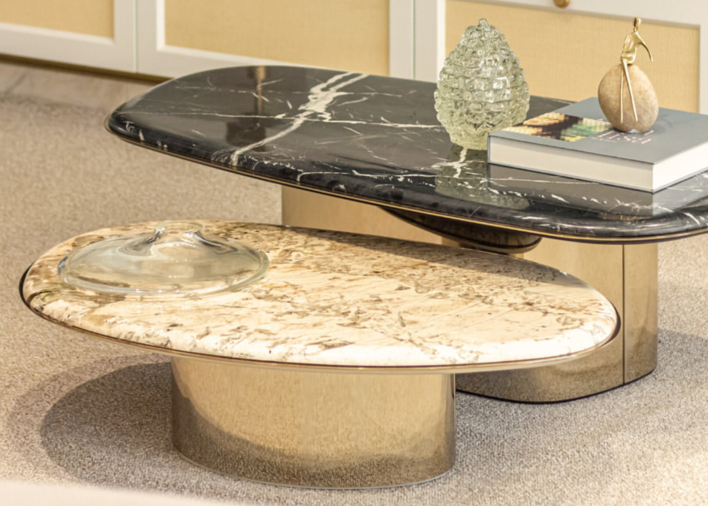 Mesa de centro tampo em mármore Nero Marquina e Alpinus, base dourada em inox polido, vista sobre fundo elegante. Peça de destaque para composições sofisticadas e elegantes.