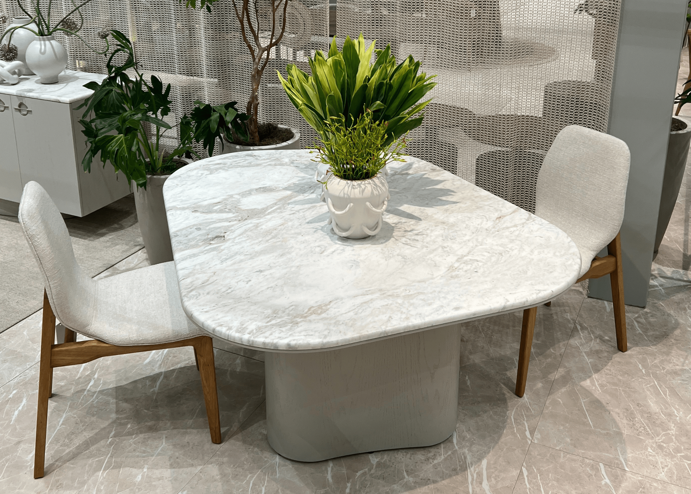 Mesa Glen em mármore branco como destaque central do ambiente, combinada com elementos naturais e neutros.