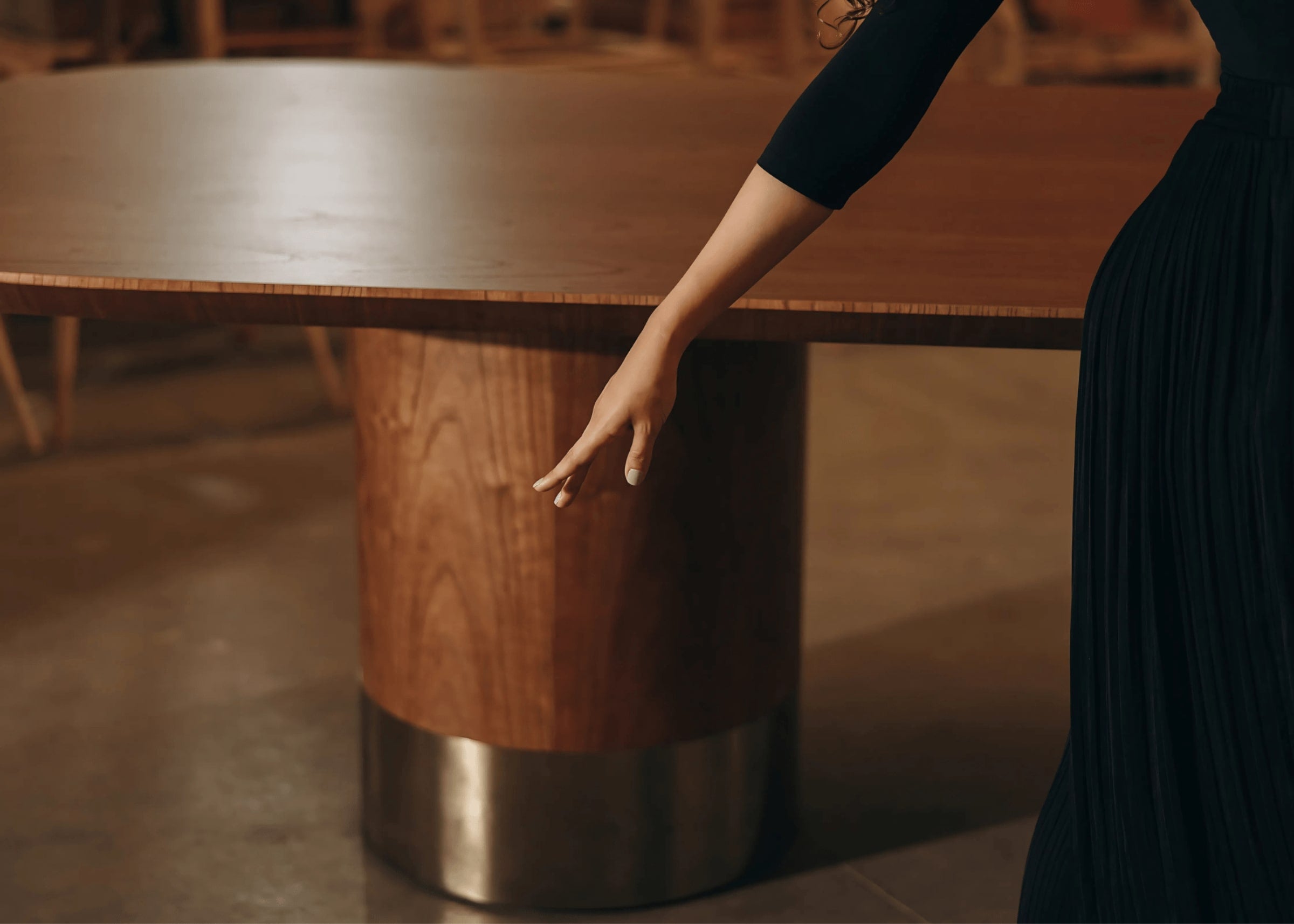 Detalhe da base cilíndrica em madeira com acabamento metálico da mesa de jantar Heron – sofisticação e acabamento refinado.