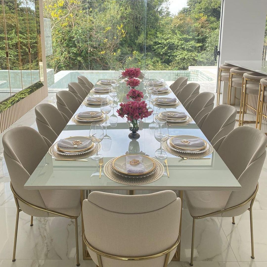 Mesa de jantar retangular Eldorado com tampo laqueado branco com vidro para 12 lugares, cadeiras estofadas Green e acompanhada por banquetas altas Eldorado em aço inox gold. Sala de jantar elegante com móveis exclusivos e personalizados da Moveca Decor.