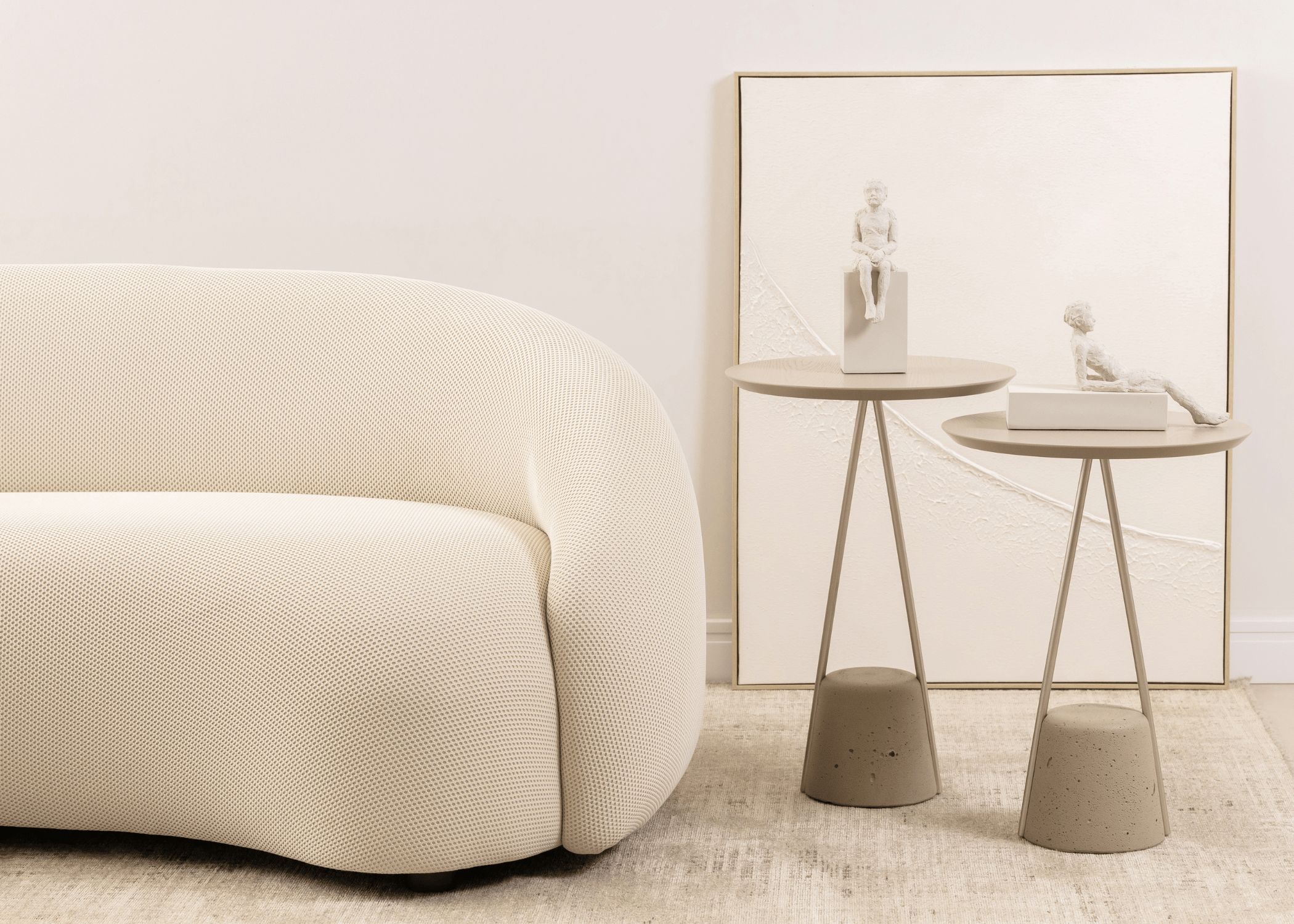 Mesa lateral Lola ao lado de sofá de linhas orgânicas em ambiente clean, perfeita para complementar a decoração de salas de estar contemporâneas.