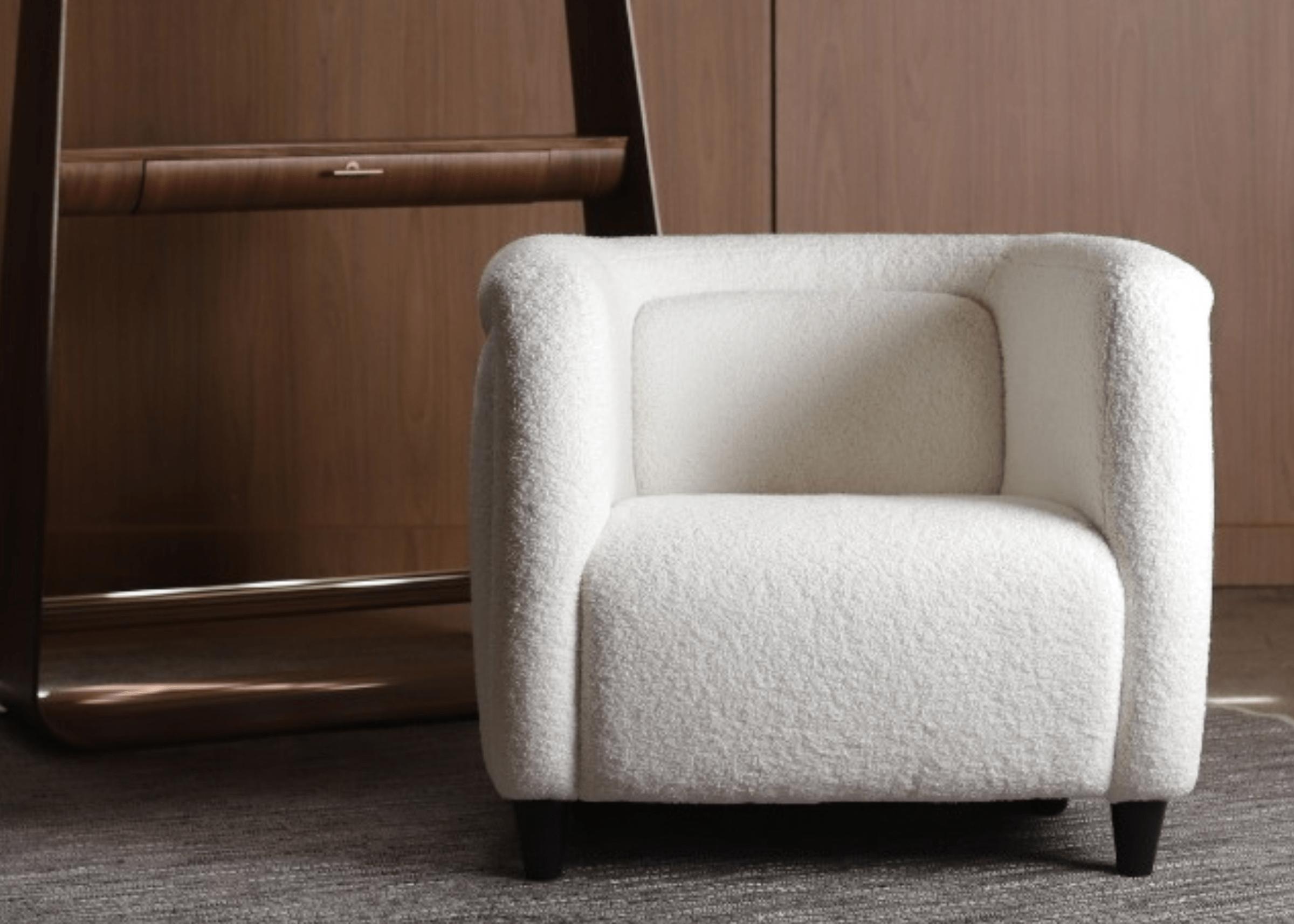 Poltrona Argos estofada em bouclé claro com pés de madeira, em ambiente moderno com decoração minimalista.
