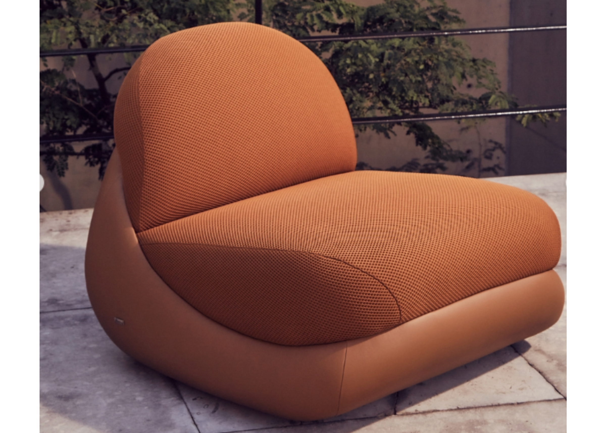 Poltrona Atmosfera com base em couríssimo caramelo e assento e encosto em tecido malha, oferecendo conforto, elegância e design contemporâneo para salas de estar sofisticadas.