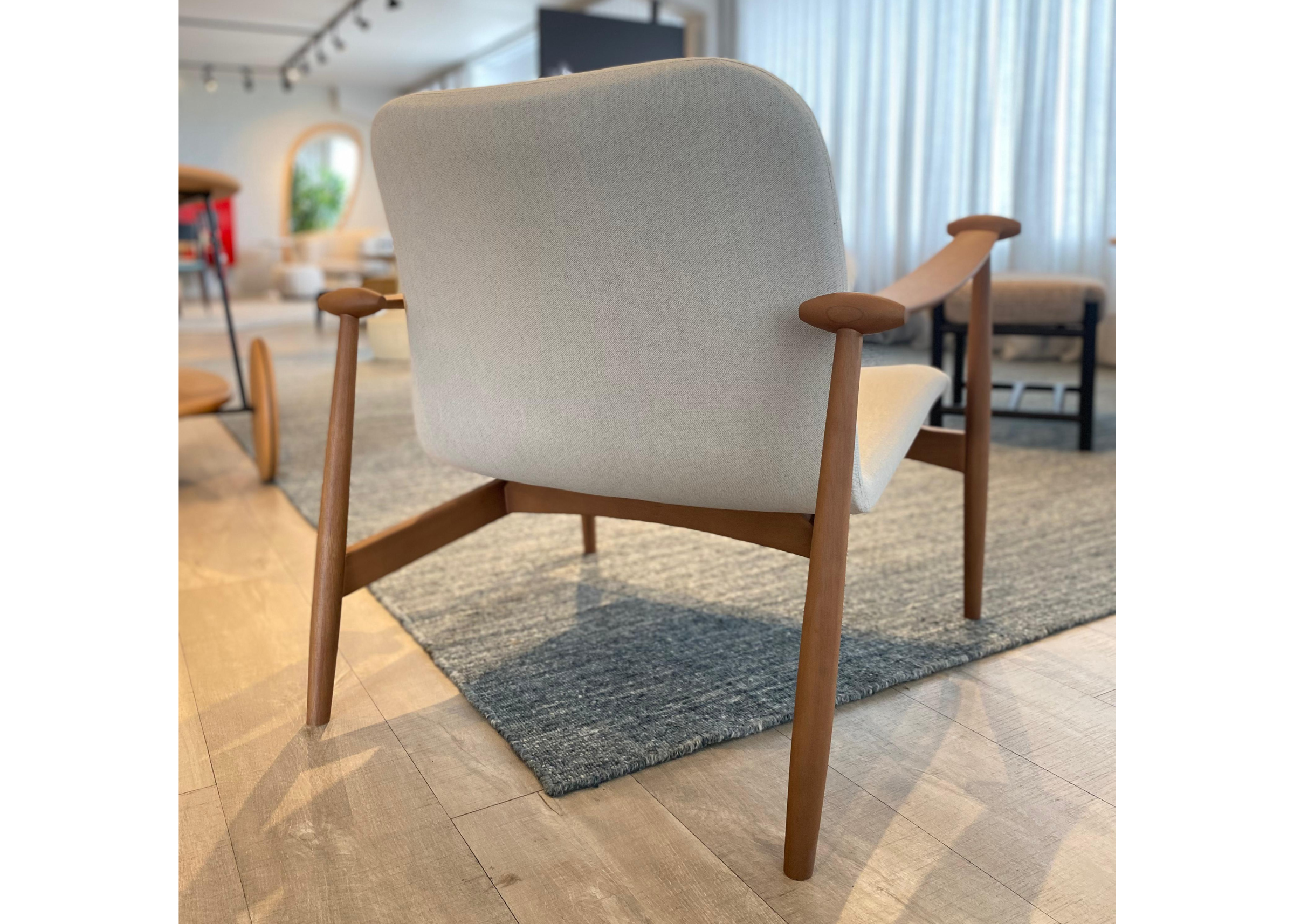 Poltrona estofada em linho com detalhes na base em madeira tingida, combinando conforto, elegância e sofisticação ao ambiente.