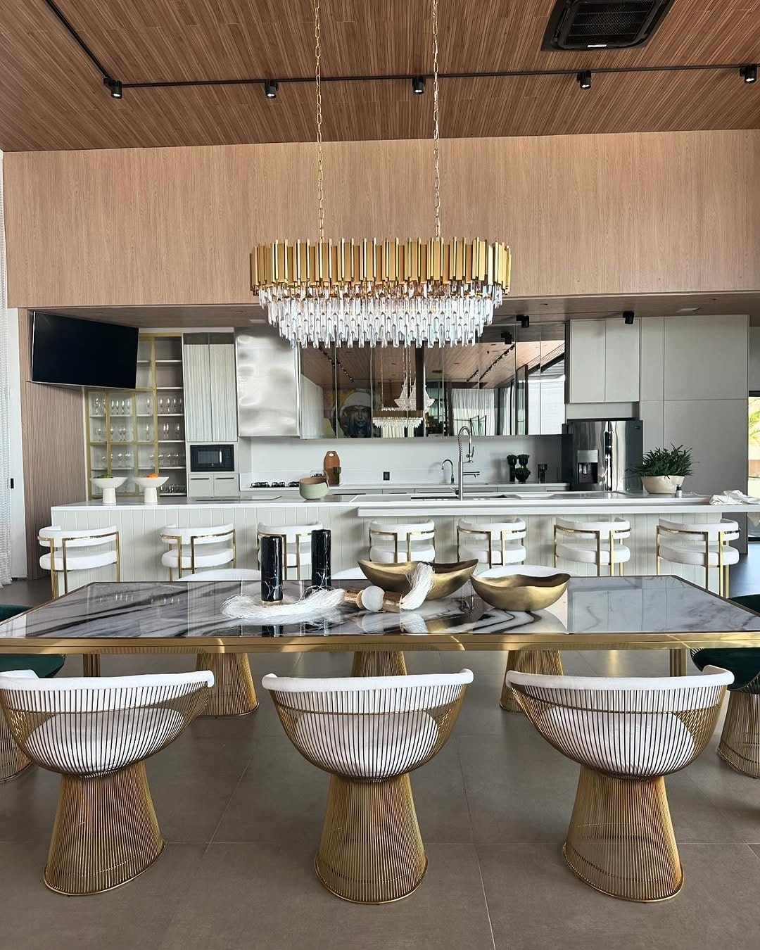 Restaurante contemporâneo com mesa de jantar em mármore, cadeiras Platner e banquetas Eldorado em aço inox dourado – projeto assinado por Mariana Maran com móveis da Moveca Decor.