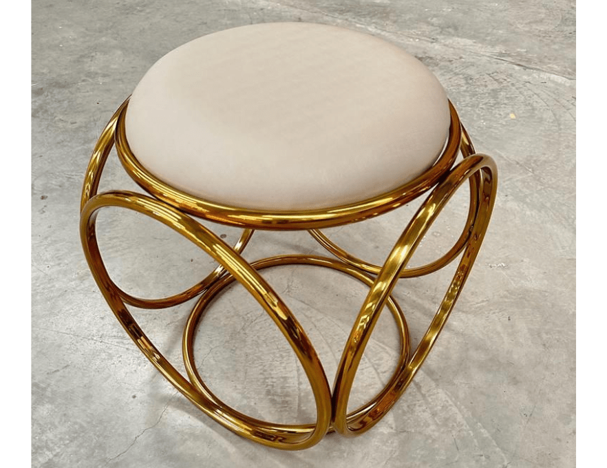 Puff luxo dourado com estrutura metálica circular e assento estofado veludo bege. Estilo moderno e decorativo para ambientes refinados.