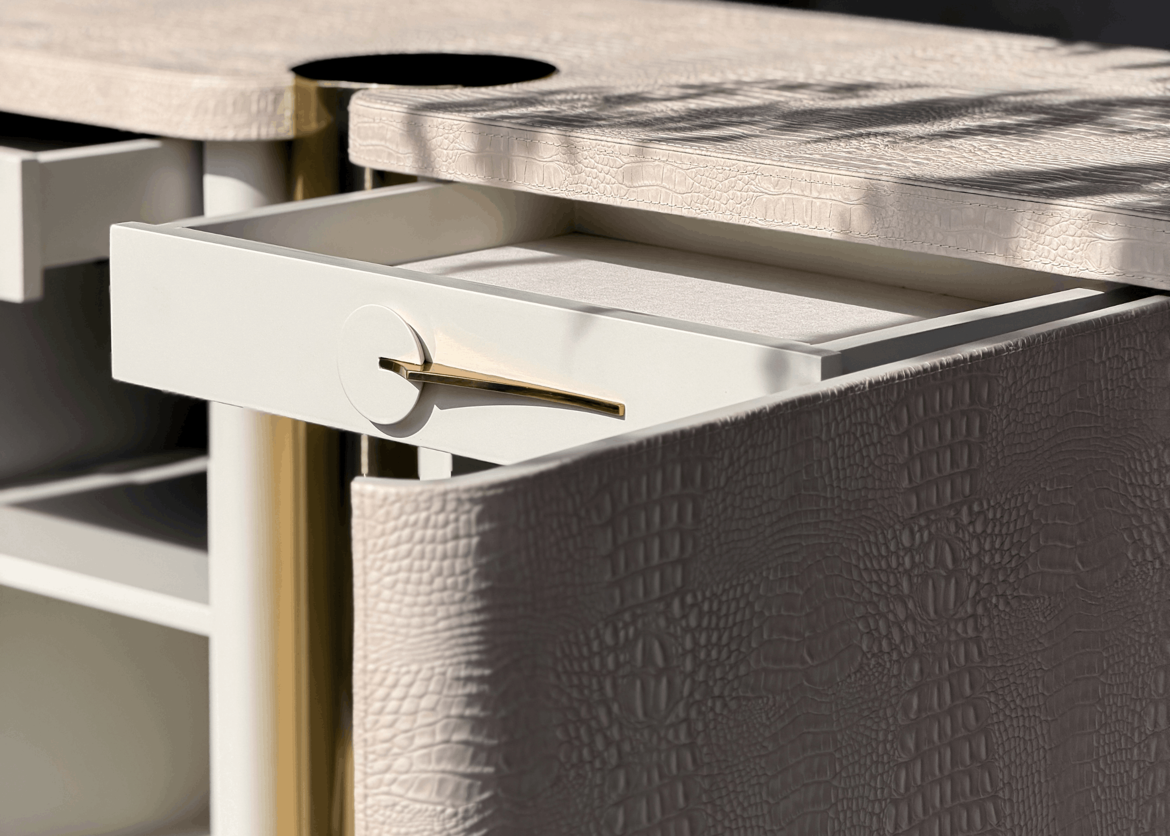 Detalhe da Cômoda Heron com textura croco em laca e coluna central em aço inox dourado, destacando acabamento refinado e design exclusivo.