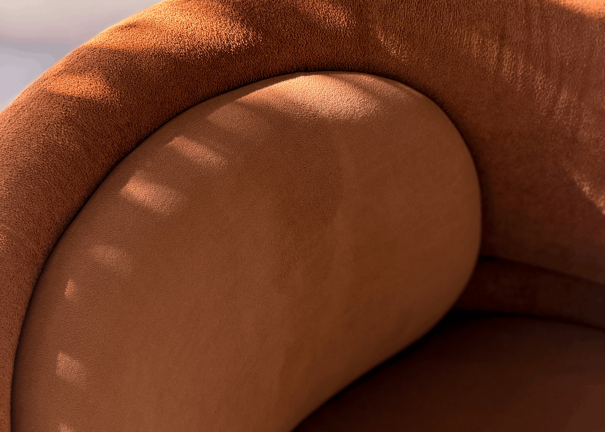 Close da Poltrona Giratória Luci evidenciando a textura do tecido e o desenho curvo do braço integrado ao encosto.