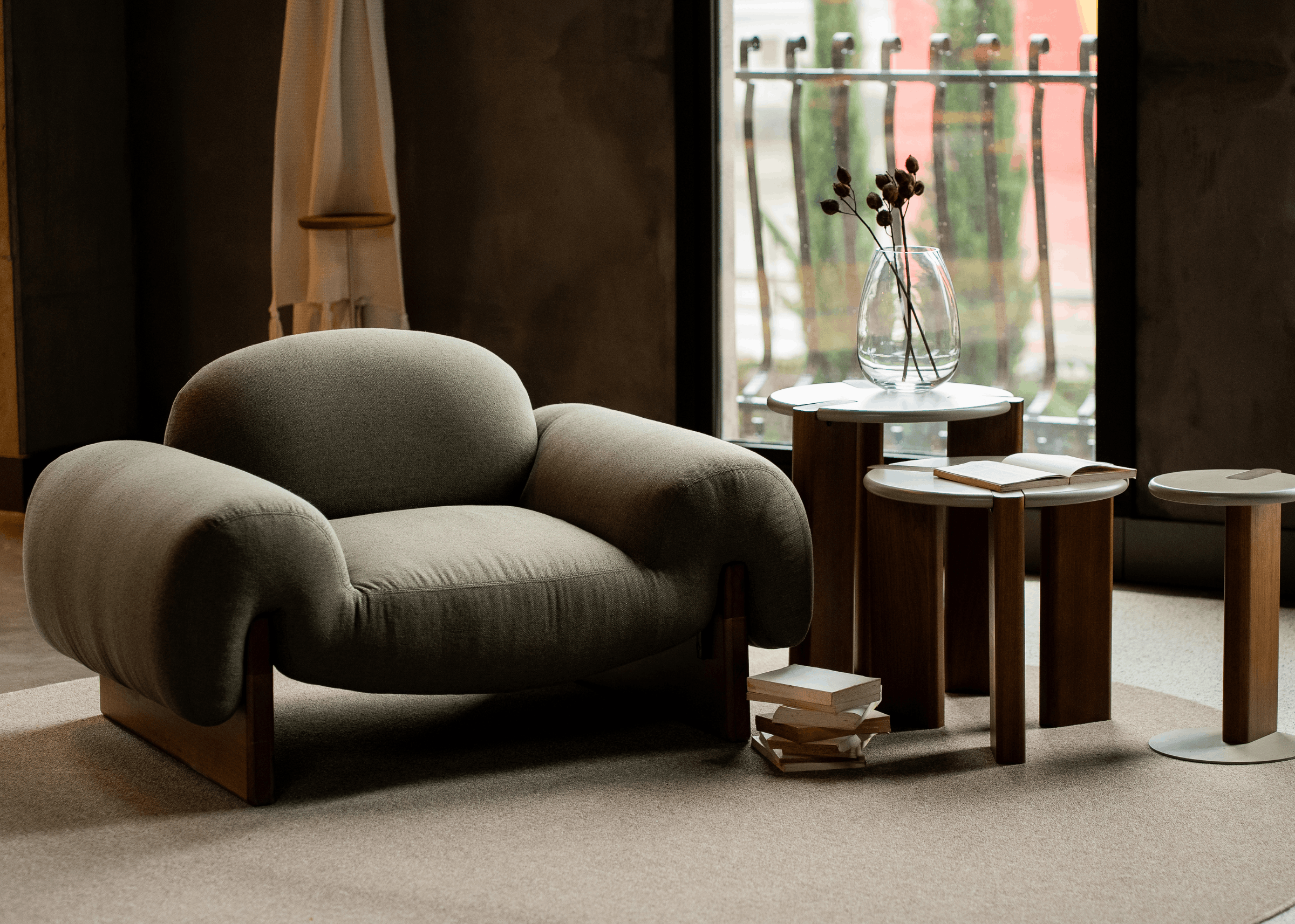 Poltrona Lana em sala de estar contemporânea com mesas laterais e decoração minimalista, estofado verde oliva e base em madeira.