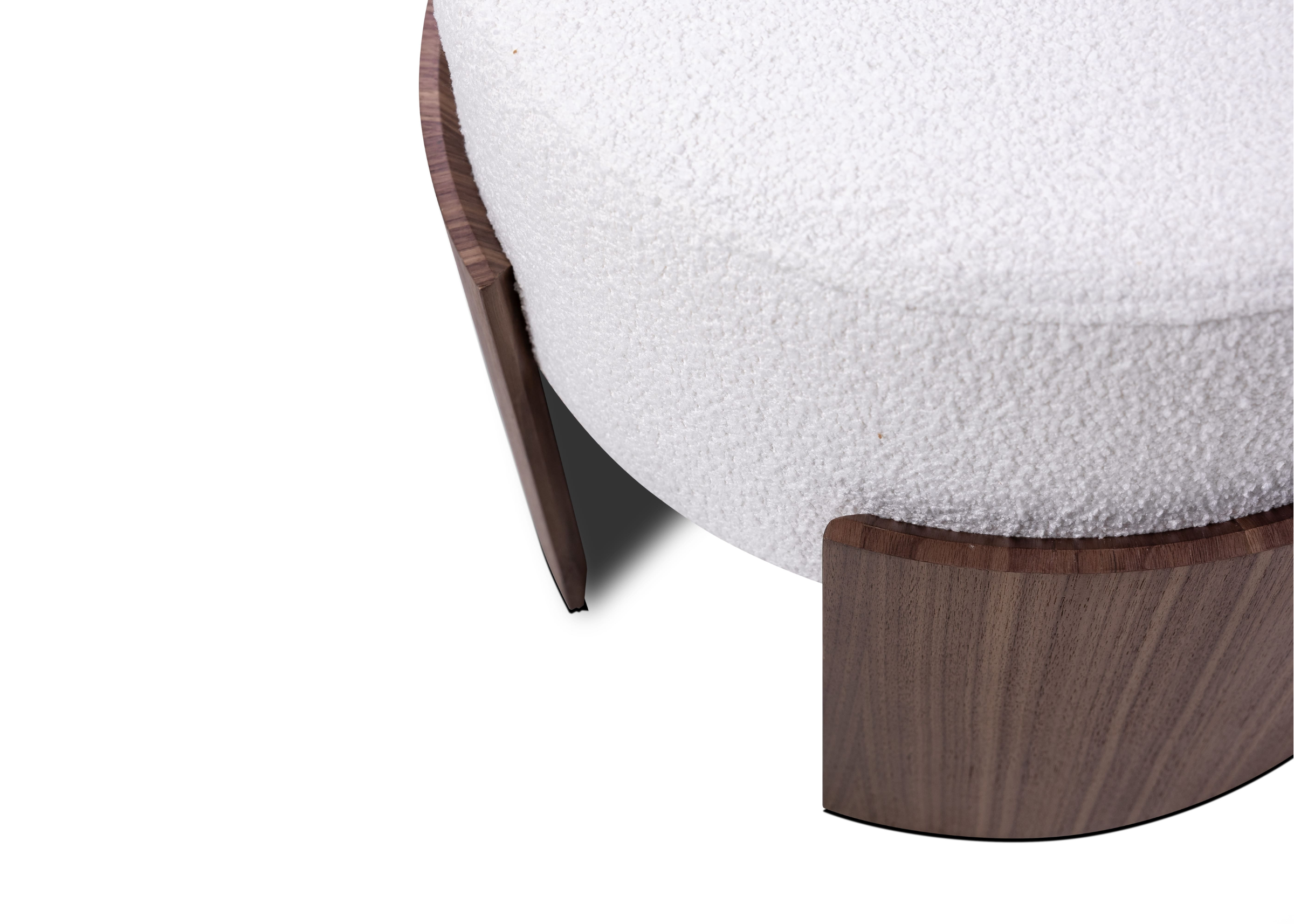 Puff Adria com formas orgânicas, assento confortável e base curva em madeira, ideal para decoração sofisticada e acolhedora.