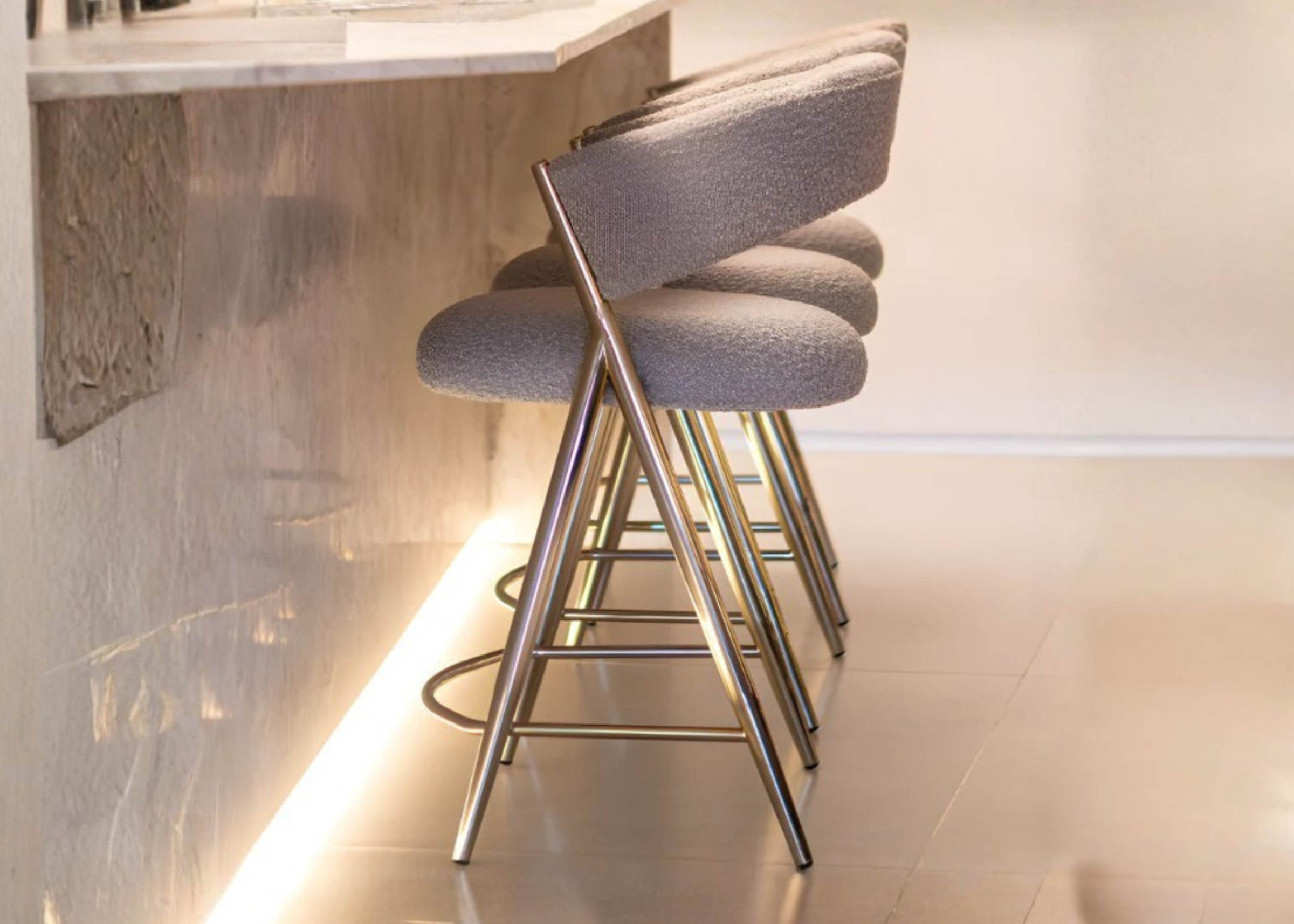 Banqueta Channel com base em aço inox dourado Golden e assento em tecido bouclé, combinando luxo, conforto e sofisticação ao ambiente.