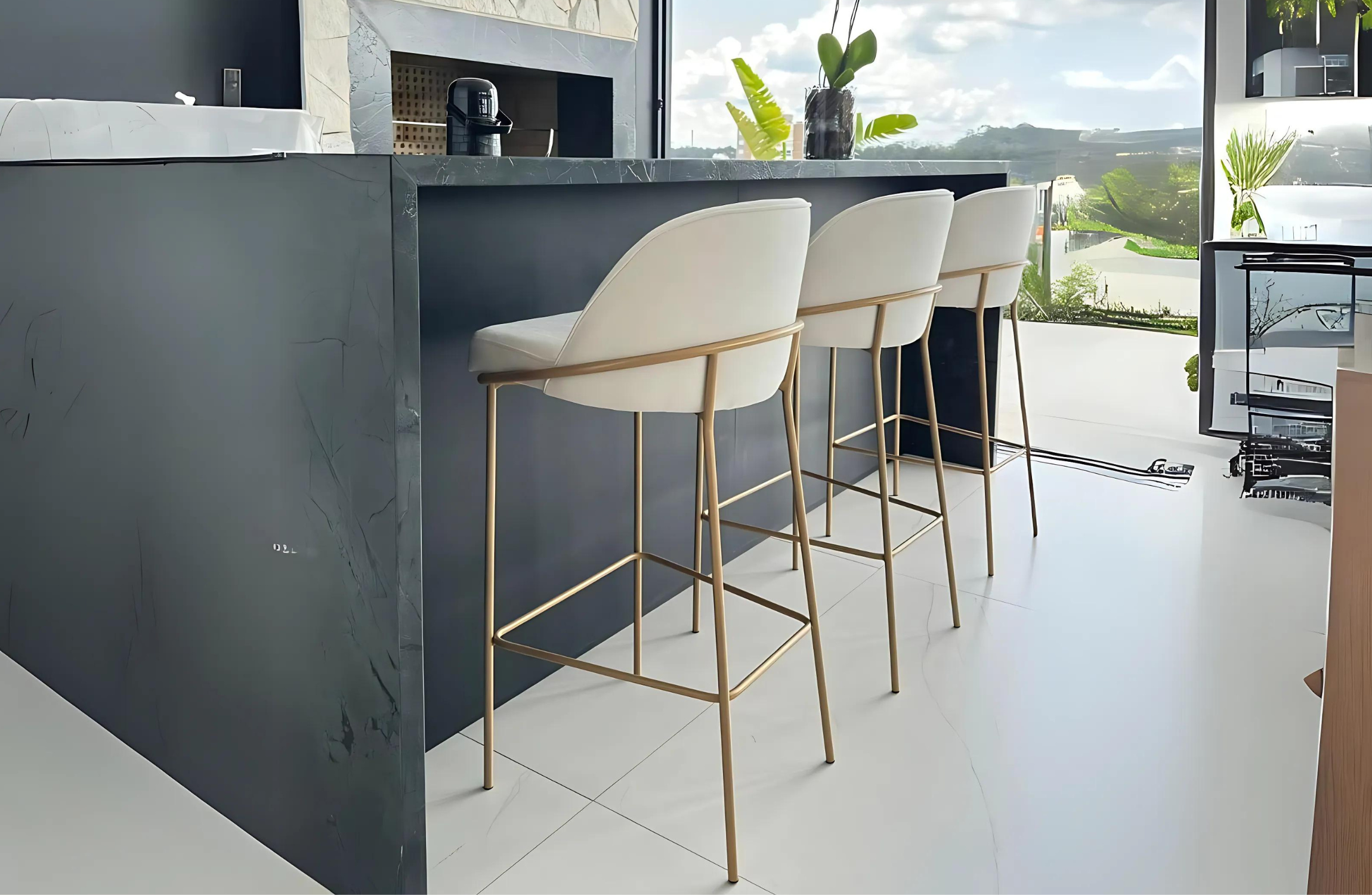 Banqueta Blue elegante e estofada em tecido off-white, com base dourada, ambientada em cenário sofisticado. Móvel refinado e funcional para bancadas e áreas gourmet modernas.