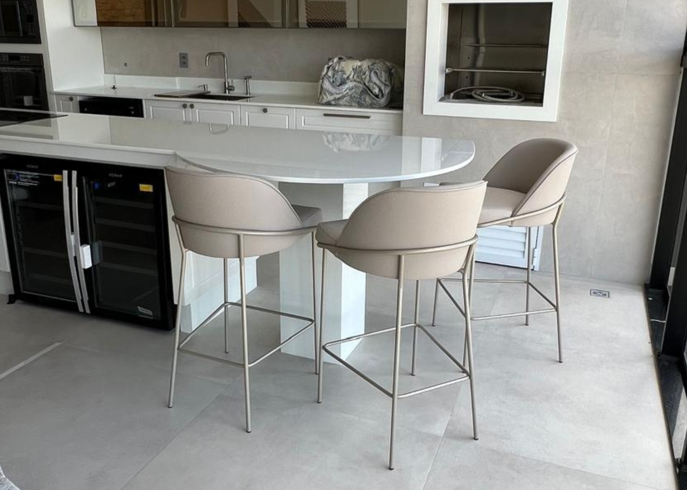 Banqueta Blue moderna e sofisticada, estofada em tecido off-white, disposta em bancada. Móvel elegante e funcional para áreas gourmet contemporâneas.