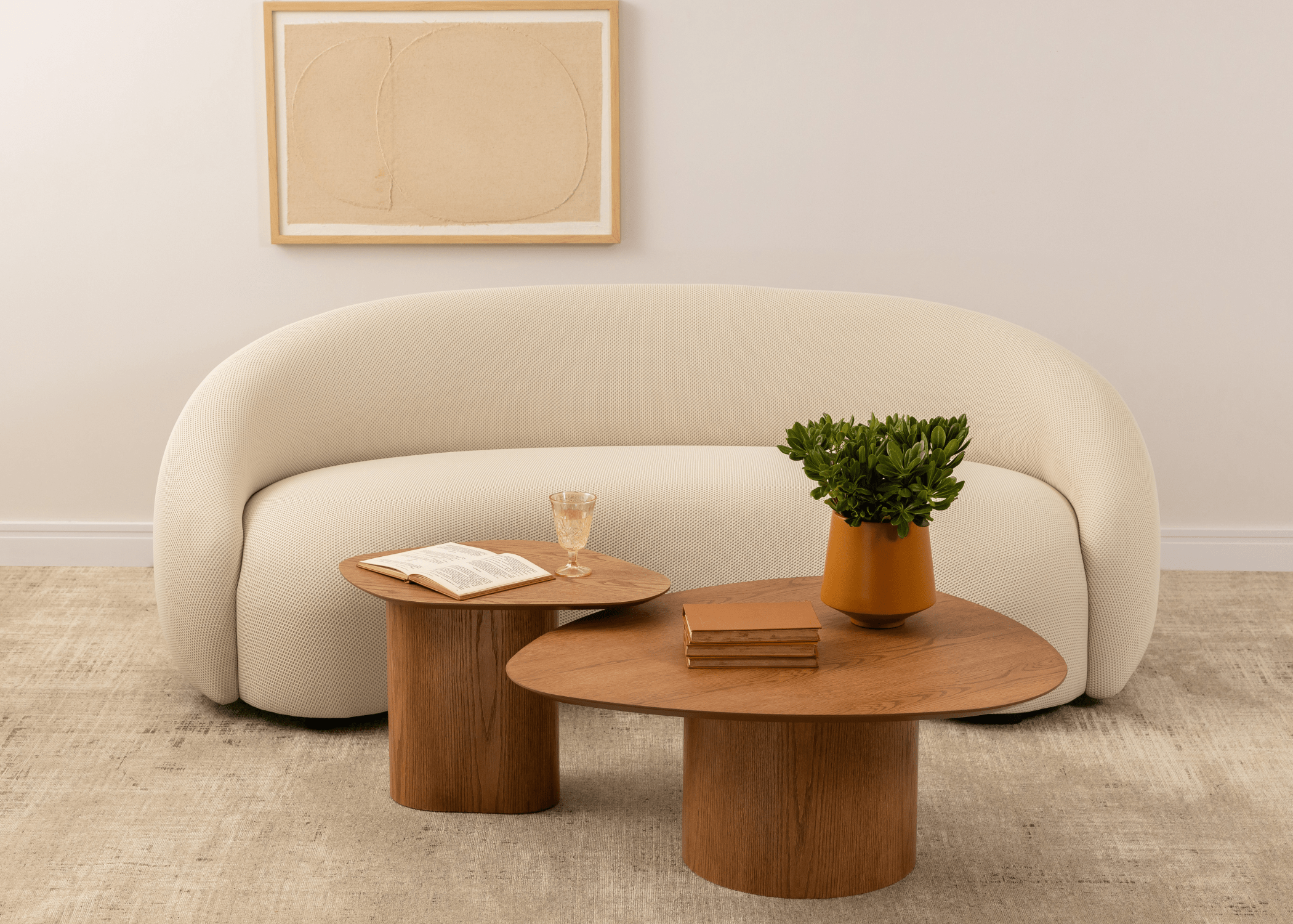 Mesa de centro orgânica Raiver posicionada à frente de sofá moderno curvo bege.