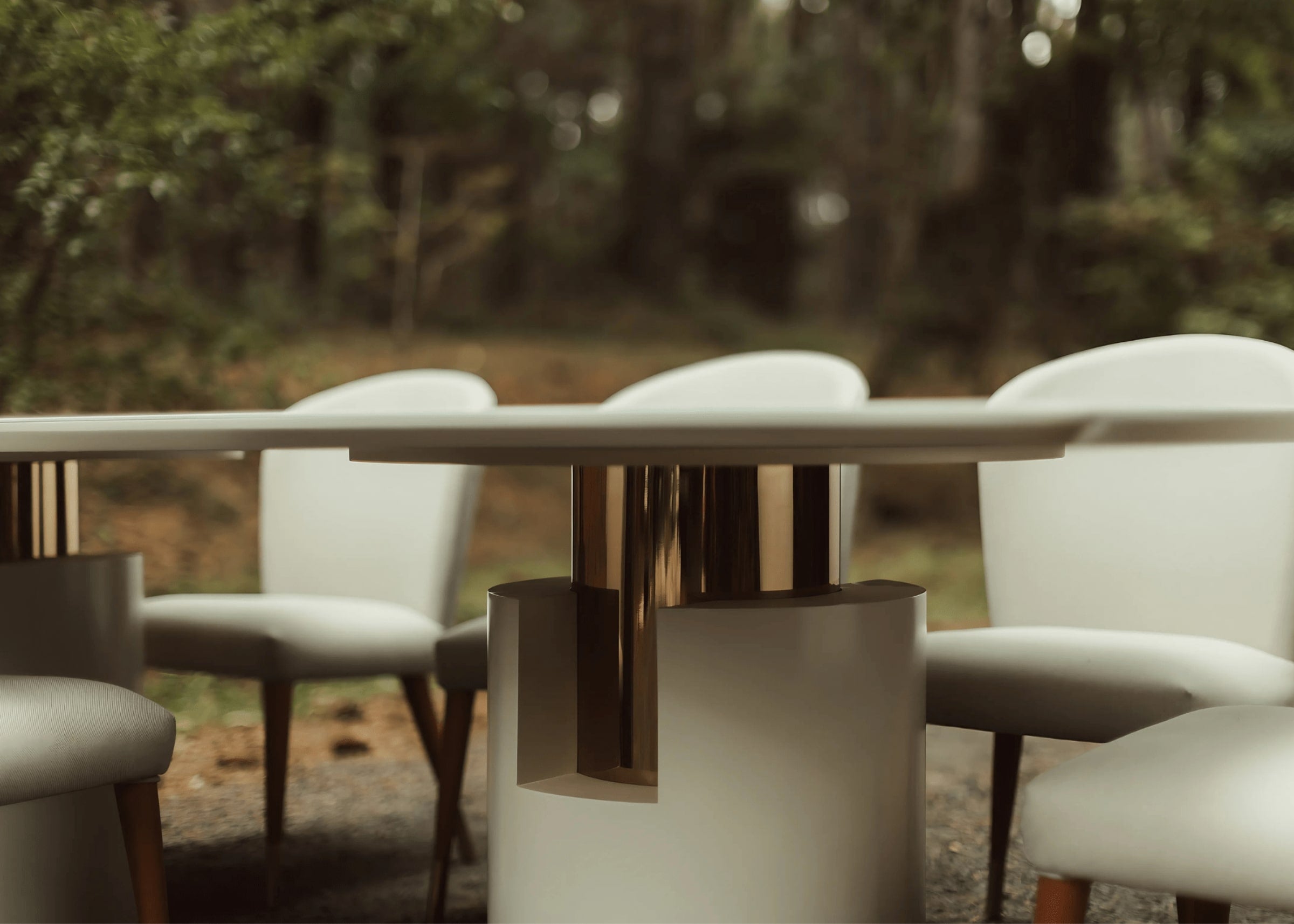 Detalhe do design da base cilíndrica da mesa de jantar moderna Theodoro com inox dourado.