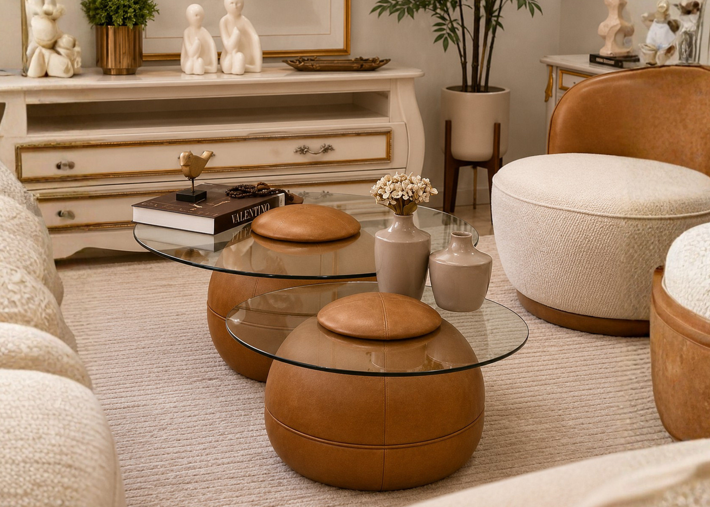 Mesa de centro Stella em sala moderna com base em couro caramelo e tampo de vidro transparente, apresentando design elegante e sofisticado para compor ambientes refinados.