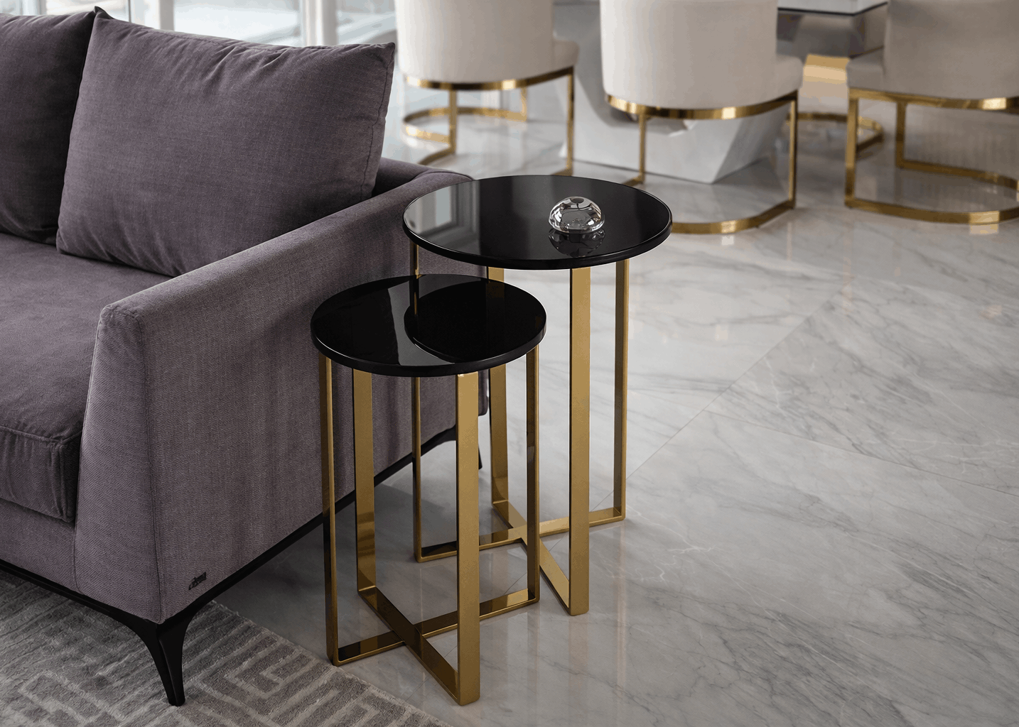 Conjunto de mesas laterais Dreams com base dourado gold e tampo laca preto com vidro ao lado do sofá em sala de estar sofisticada.