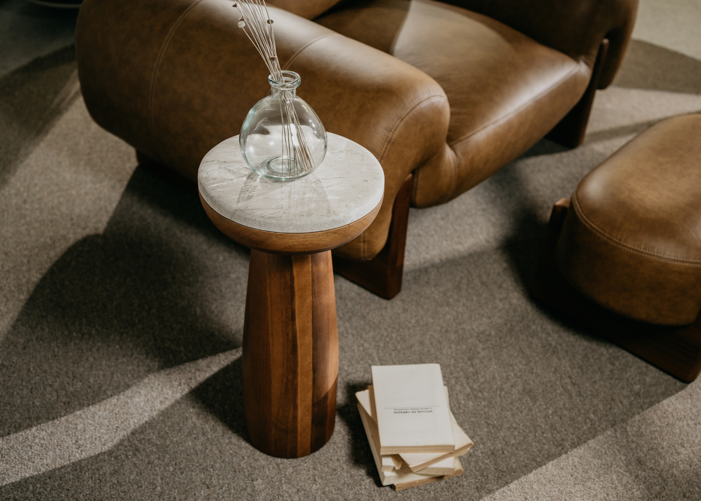 Mesa de Apoio Liam com tampo em mármore travertino de veios naturais e base robusta em madeira, peça elegante e atemporal.