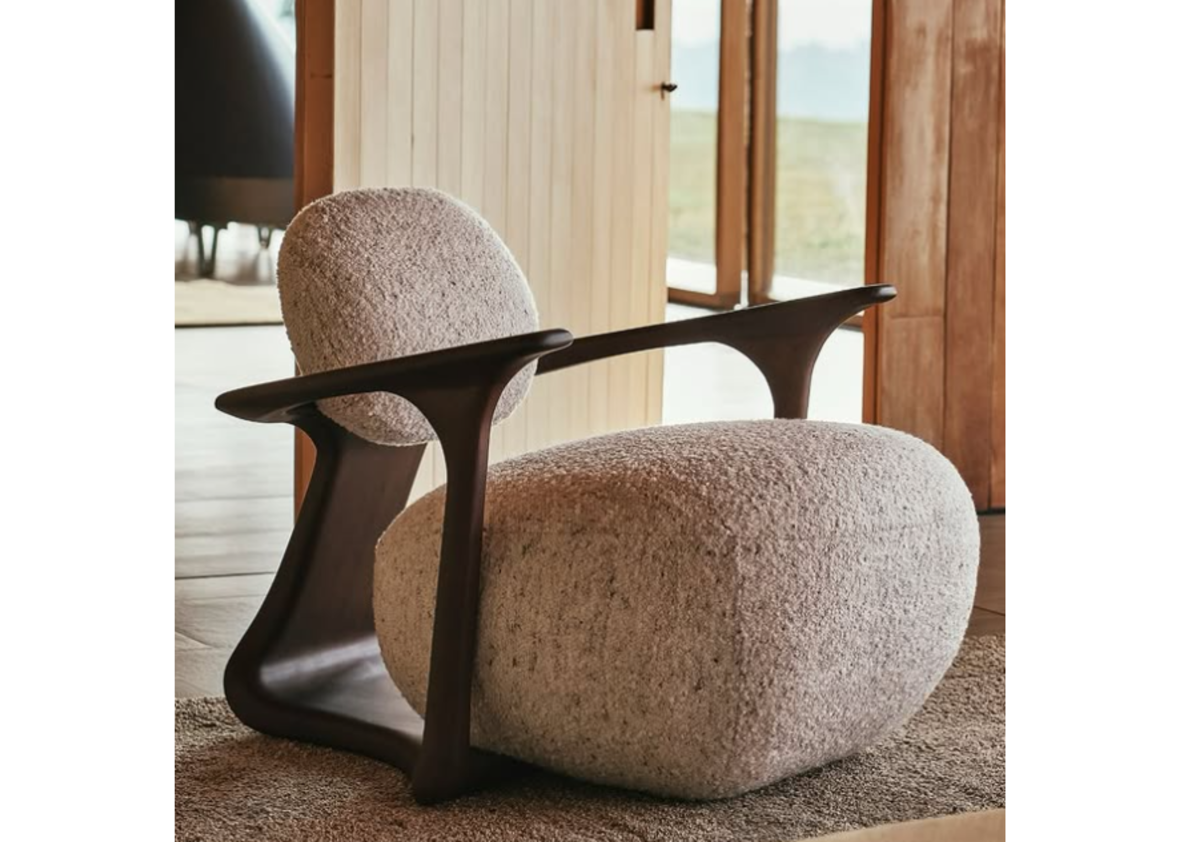 Poltrona Ícone com revestimento em bouclé off white e base em madeira, ambientada em espaço elegante e acolhedor, com design sofisticado e conforto.