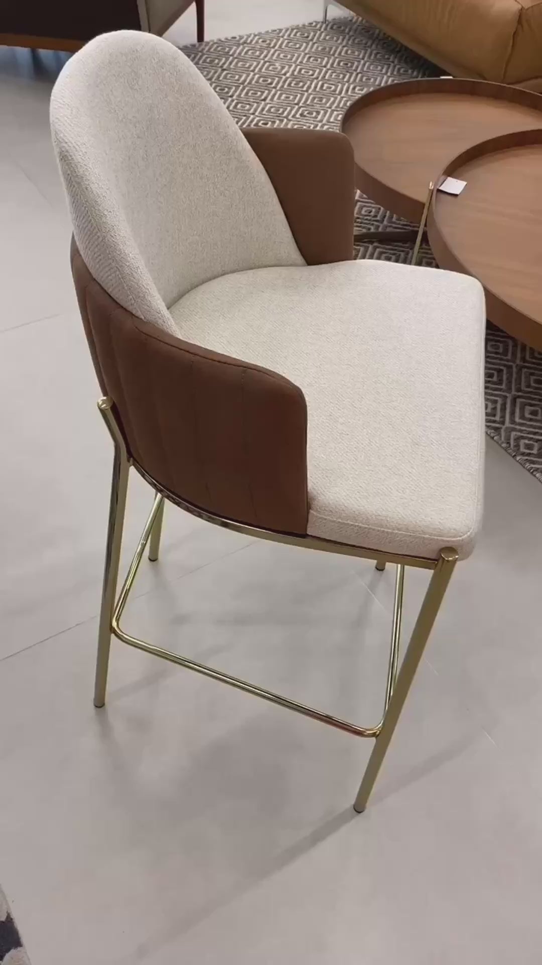 Banqueta Janette estofada com encosto curvo e base em aço carbono, ideal para bancada gourmet e cozinha moderna sofisticada.