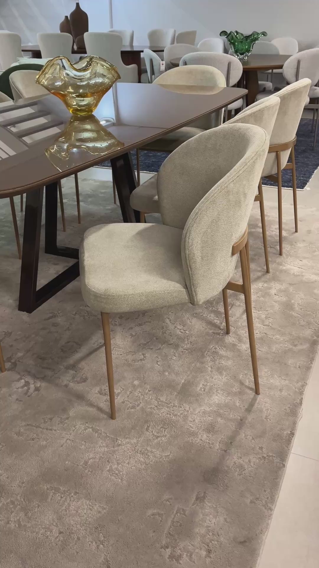 Cadeira Noa moderna estofada com base em aço carbono dourado e design sofisticado, ideal para sala de jantar de alto padrão.